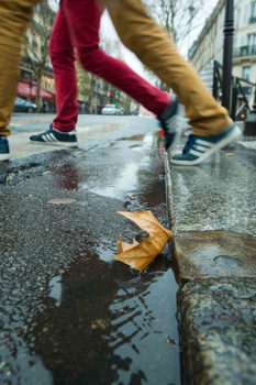 Feet of people jumping over a puddle